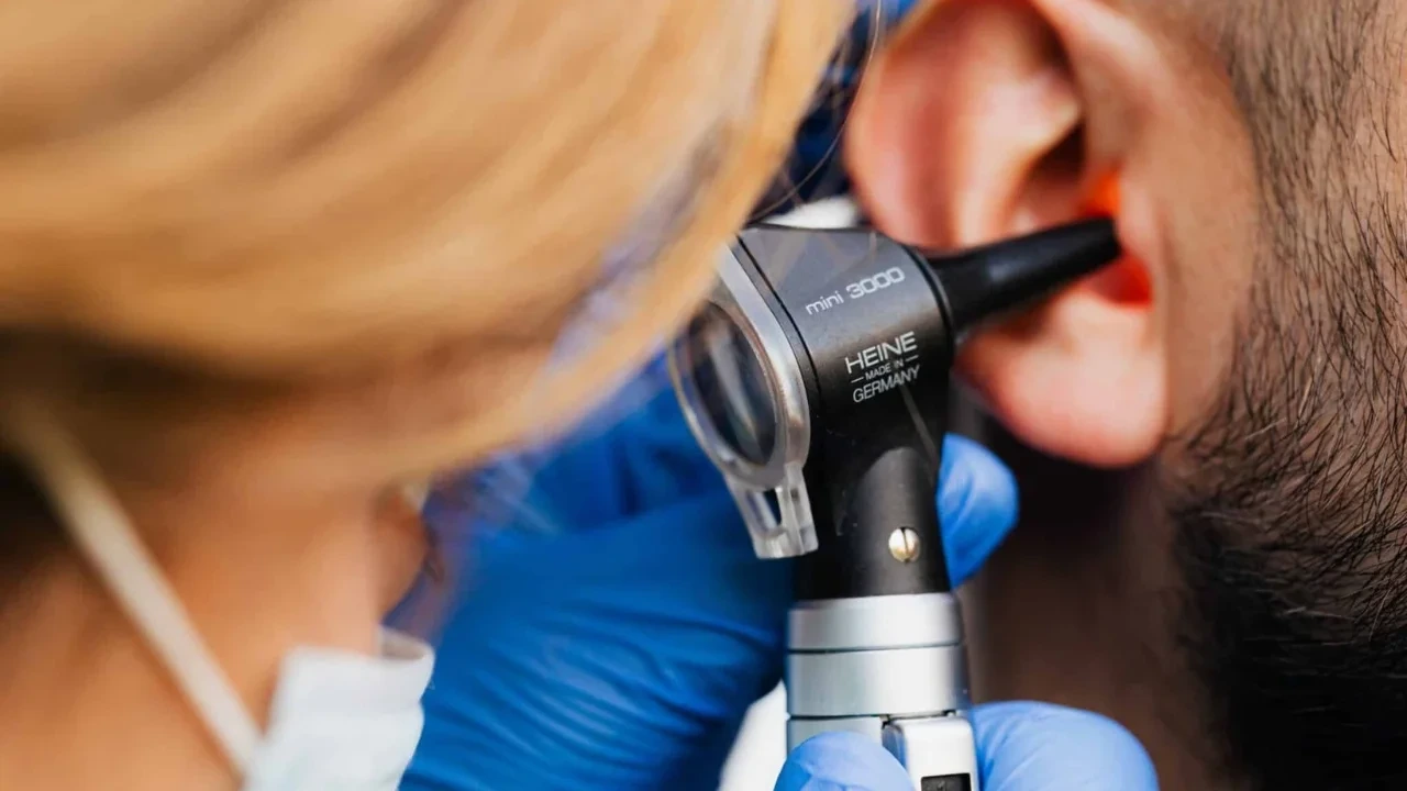 Clinician examining an ear with an otoscope